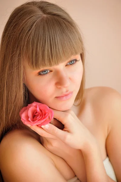 Krásná dívka s růžovou květinou dotýká její tvář. péče o pleť konc — Stock fotografie