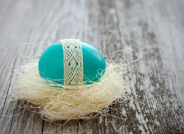 Huevo azul de Pascua está en un nido sobre un viejo fondo de madera — Foto de Stock