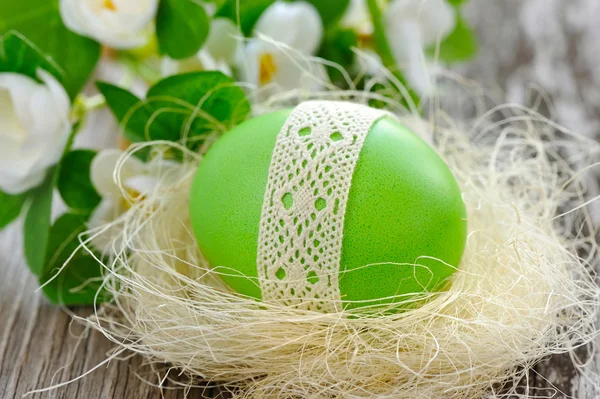 Easter green egg is in a nest on a old wooden background — Stock Photo, Image