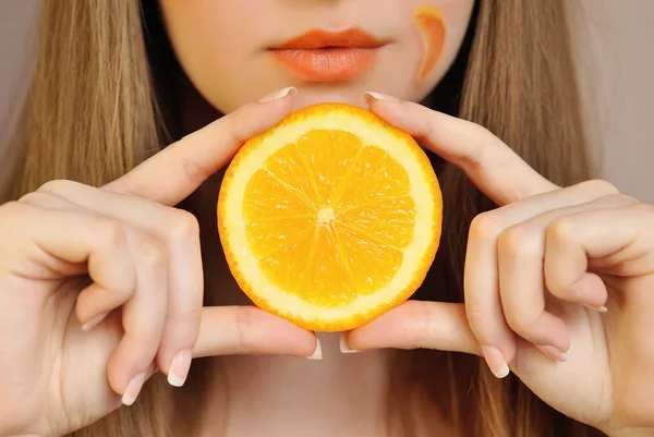 Jovem mulher bonita com fatia de laranja nas mãos — Fotografia de Stock