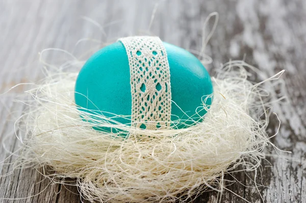 Huevo azul de Pascua está en un nido sobre un viejo fondo de madera — Foto de Stock