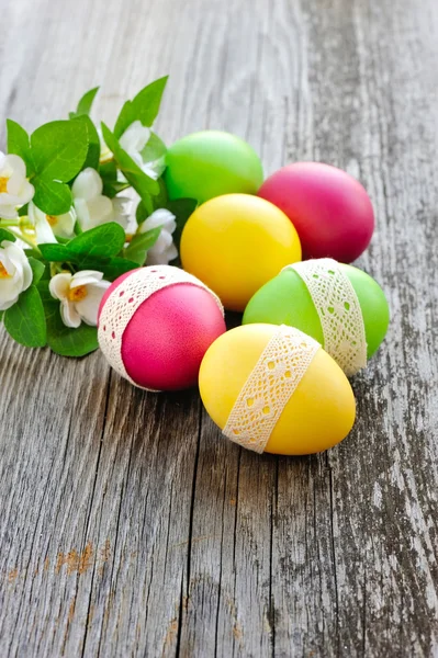 Eski ahşap bir masa üzerinde renkli Paskalya yumurtaları — Stok fotoğraf