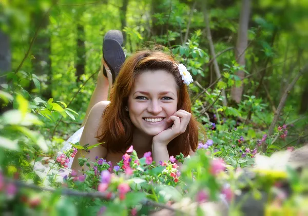 Beautiful young woman in the forest with spring flowers — Stock Photo, Image