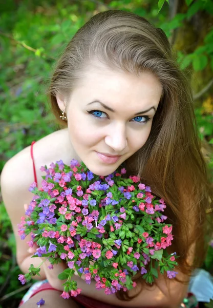 Beautiful young woman with the bouquet of spring flowers — Stock Photo, Image