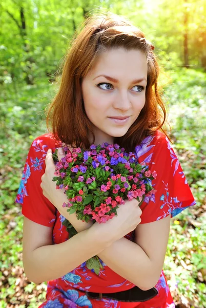 Belle jeune femme avec le bouquet de fleurs de printemps — Photo