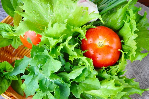 Fresh vegetables and greenery are in a basket on a old wooden background — Stock Photo, Image