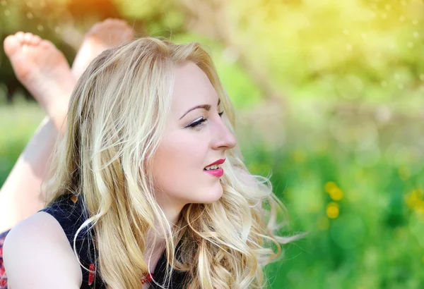 Schönes Mädchen, das im Sommergras liegt — Stockfoto