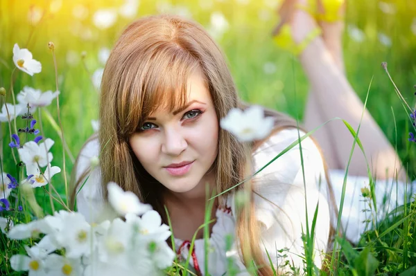 Belle jeune femme sur la prairie avec des fleurs blanches par une chaude journée d'été — Photo