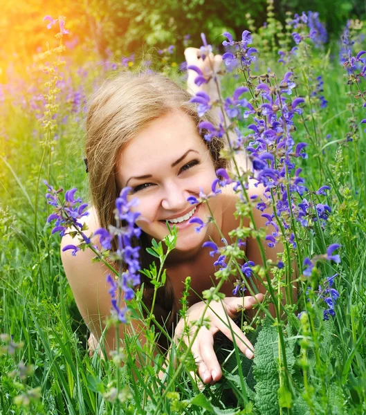 Mooie jonge vrouw in violette bloemen buitenshuis — Stockfoto