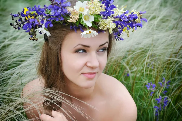 Belle jeune femme avec une couronne de fleurs dans l'herbe de plumes-herbe à l'extérieur — Photo