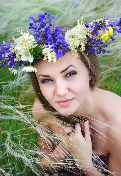Bella giovane donna con corona di fiori nell'erba di piuma-erba all'aperto — Foto Stock