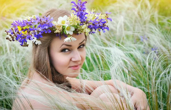 Mulher bonita com coroa de flores na grama de penas-grama ao ar livre — Fotografia de Stock