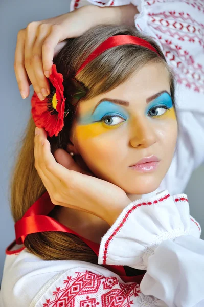 Retrato de una mujer con maquillaje creativo Bandera de Ucrania en su cara en el traje nacional de Ucrania — Foto de Stock