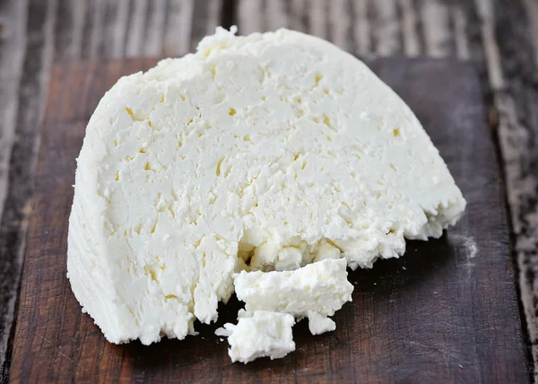 A piece of cheese on a wooden board — Stock Photo, Image