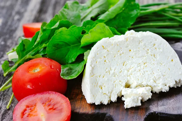 Cheese with tomatoes and arugula and onion — Stock Photo, Image