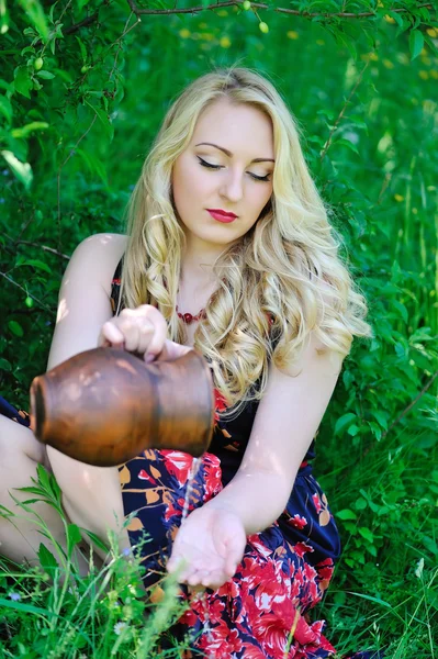 Retrato de una hermosa mujer rubia con una jarra de cerámica — Foto de Stock