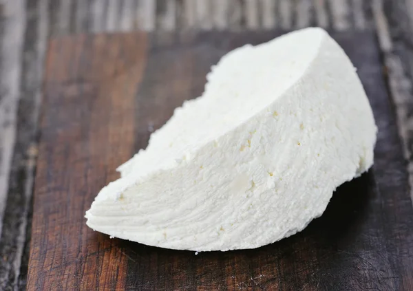 A piece of cheese on a wooden board — Stock Photo, Image