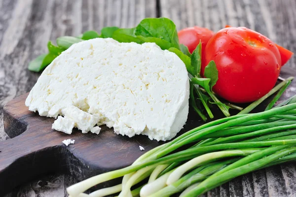 Queso con tomates y rúcula y cebolla sobre una tabla de madera —  Fotos de Stock