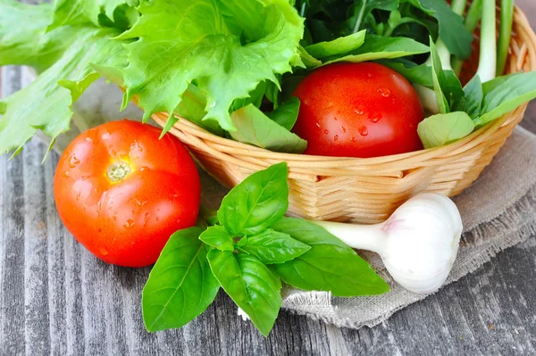 Frisches Gemüse und Grünzeug liegen in einem Korb auf altem Holzgrund — Stockfoto