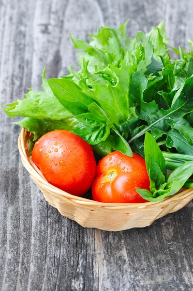 Légumes frais et verdure sont dans un panier sur un vieux fond en bois — Photo