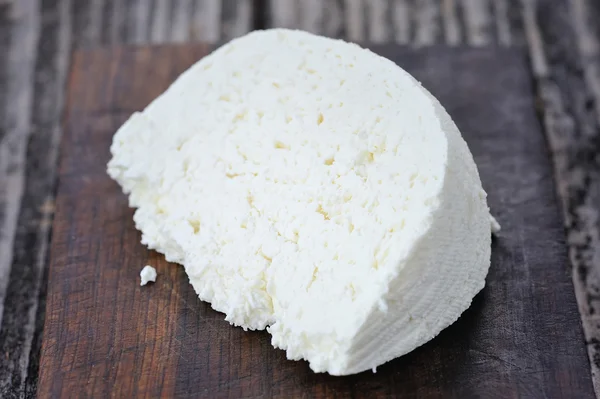 Een stuk kaas op een houten plank — Stockfoto
