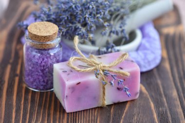 Ahşap masadaki lavanta spa ürünleri. Lavantalı vücut bakım ürünleri: sabun, tuz ve kurutulmuş lavanta çiçekleri. Seçici odak.