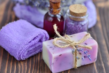 Ahşap masadaki lavanta spa ürünleri. Lavantalı vücut bakım ürünleri: sabun, yağ, tuz ve kurutulmuş lavanta çiçekleri. Seçici odak.