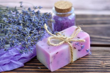 Ahşap masadaki lavanta spa ürünleri. Lavantalı vücut bakım ürünleri: sabun, tuz ve kurutulmuş lavanta çiçekleri. Seçici odak.