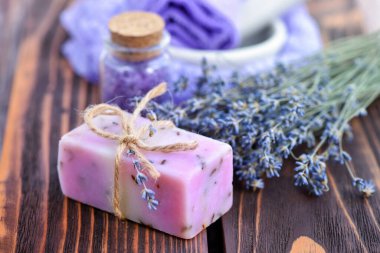 Ahşap masadaki lavanta spa ürünleri. Lavantalı vücut bakım ürünleri: sabun, tuz ve kurutulmuş lavanta çiçekleri. Seçici odak.