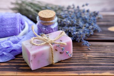 Ahşap masadaki lavanta spa ürünleri. Lavantalı vücut bakım ürünleri: sabun, tuz ve kurutulmuş lavanta çiçekleri. Seçici odak.