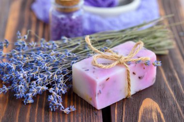 Ahşap masadaki lavanta spa ürünleri. Lavantalı vücut bakım ürünleri: sabun, tuz ve kurutulmuş lavanta çiçekleri. Seçici odak.