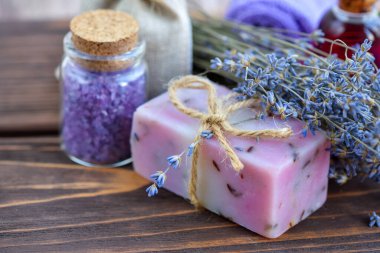 Ahşap masadaki lavanta spa ürünleri. Lavantalı vücut bakım ürünleri: sabun, yağ, tuz ve kurutulmuş lavanta çiçekleri. Seçici odak.