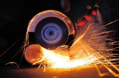 Öğütücüyle metal kesen bir işçi
