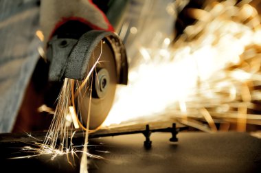 Öğütücüyle metal kesen bir işçi