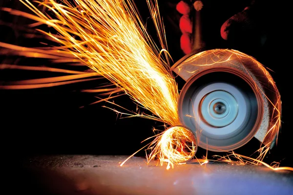 Öğütücüyle metal kesen bir işçi