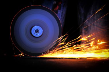 Öğütücüyle metal kesen bir işçi