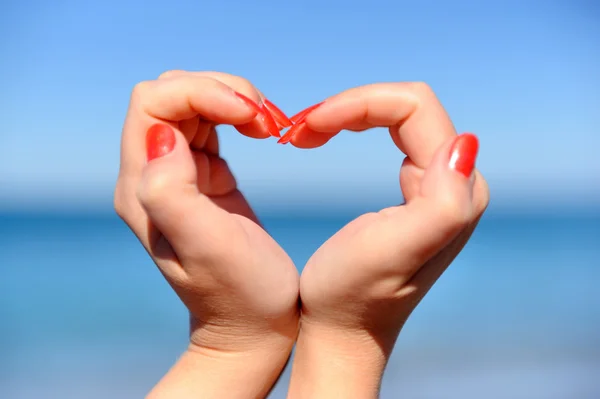 Female hand making a heart shape against — Stock Photo, Image