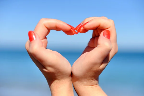 Female hand making a heart shape against — Stock Photo, Image