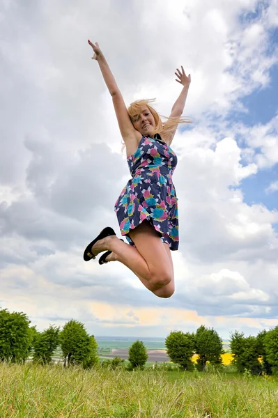 Young girl jumping high in a summer field — Stock Photo, Image