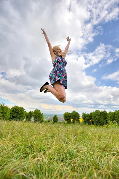 Young girl jumping high in a summer field — Stock Photo, Image