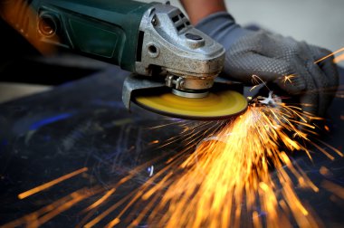 Öğütücüyle metal kesen bir işçi
