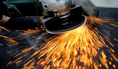 Öğütücüyle metal kesen bir işçi