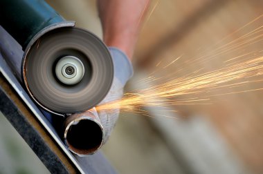 Öğütücüyle metal kesen bir işçi