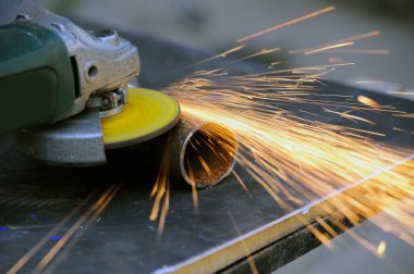 Öğütücüyle metal kesen bir işçi