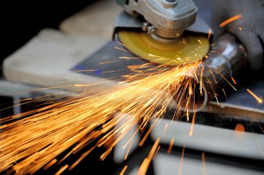 Öğütücüyle metal kesen bir işçi