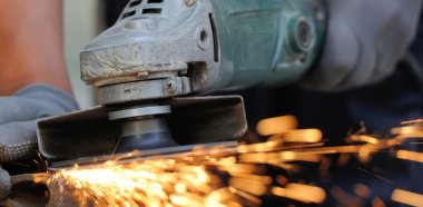 Öğütücüyle metal kesen bir işçi