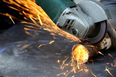 Öğütücüyle metal kesen bir işçi