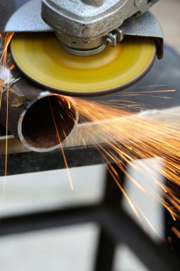 Öğütücüyle metal kesen bir işçi