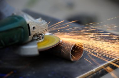 Öğütücüyle metal kesen bir işçi