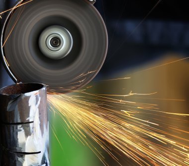 Öğütücüyle metal kesen bir işçi